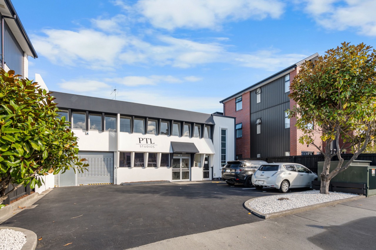 The white PTL Studios building on Cashel Street, with its car park out front
