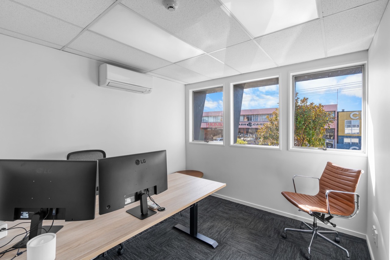 A studio with a desk, monitors and two leather chairs