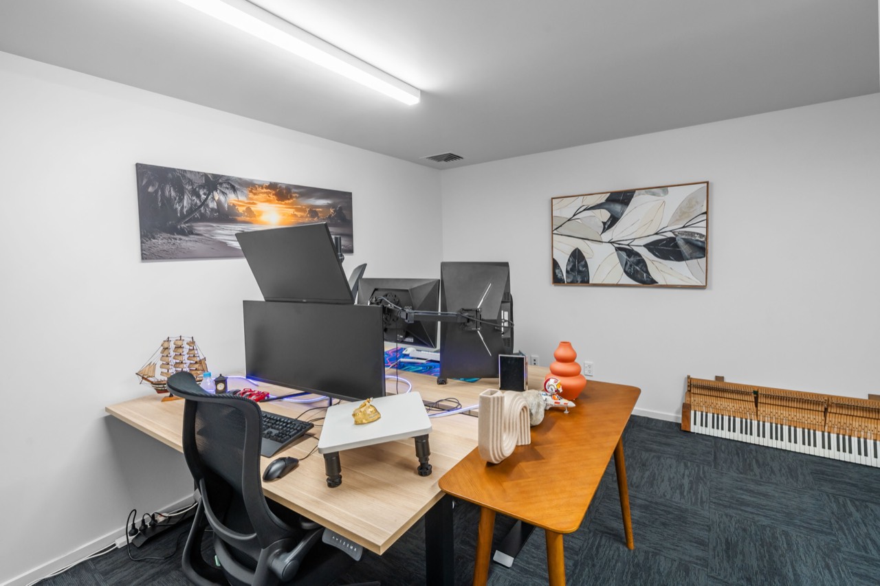 A studio set up for a small team, with a long desk and artwork on the walls